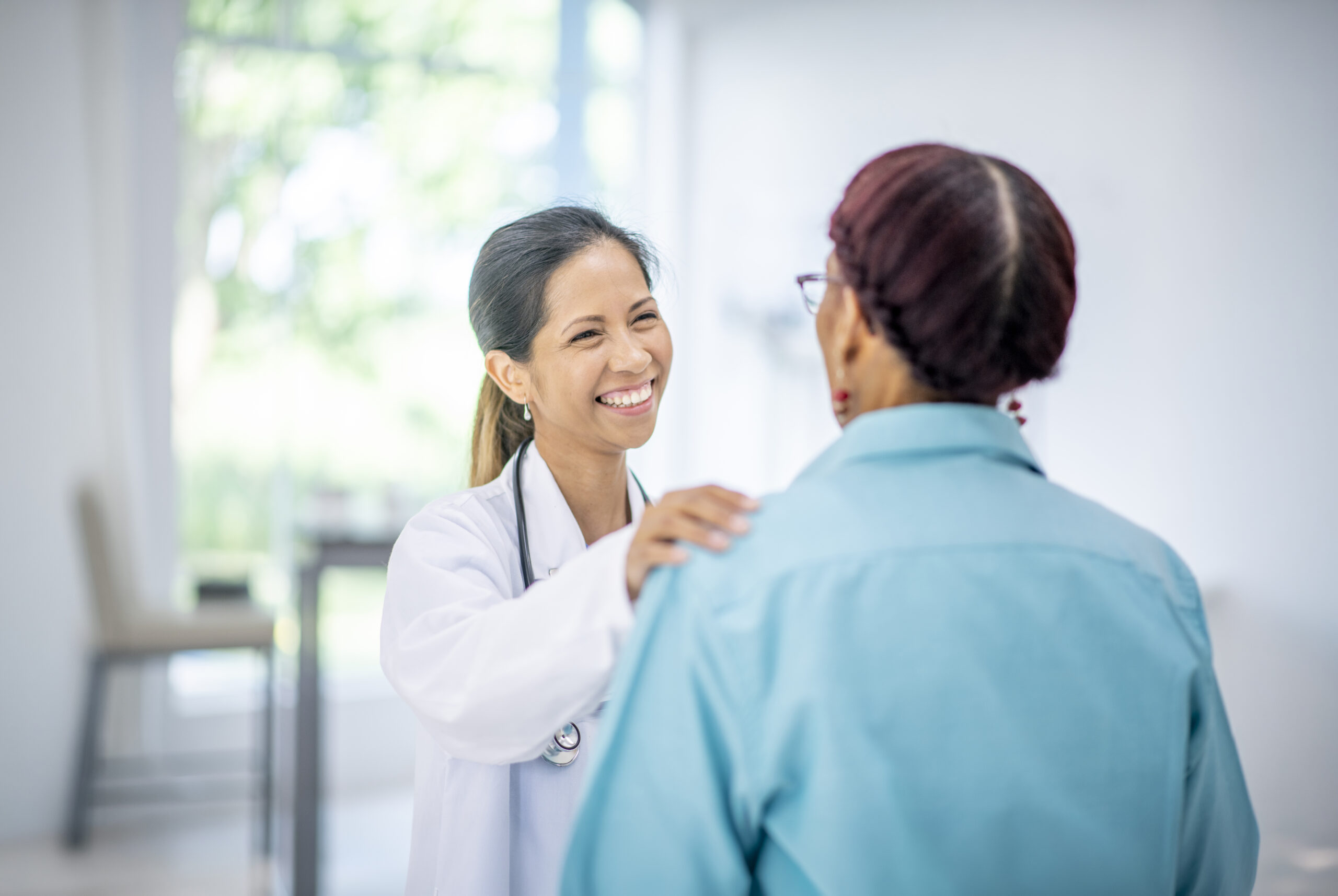 An older woman holding a document talks with a clinician during a medical visit